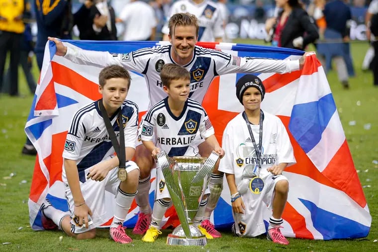 Los Angeles Galaxy's David Beckham, top center, of England, poses with his sons, from left, Brooklyn, Romeo and Cruz after the Galaxy's 3-1 win in the MLS Cup championship soccer match against the Houston Dynamo in Carson, Calif., Saturday, Dec. 1, 2012. (AP Photo/Jae C. Hong)