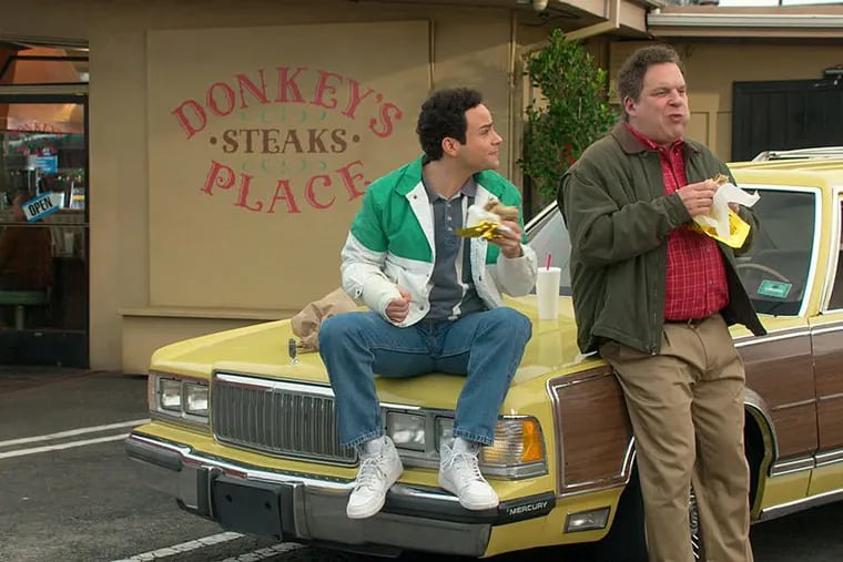 Troy Gentile (left) and Jeff Garlin eating a Donkey’s steak sandwich on “The Goldbergs.”
