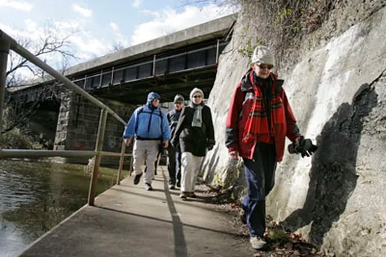 Norma Magargee of Mount Laurel (far right) and other members of her hiking group walk near a railroad trestle on Park Drive in Cooper River Park.