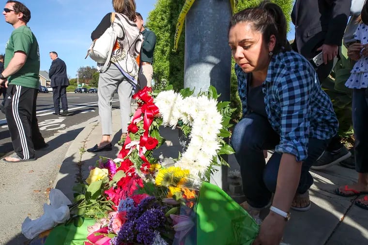 A woman leaves flowers at a small memorial near Chabad of Poway, where a man with a gun shot multiple people inside the synagogue, killing one, on Saturday in Poway, Calif.