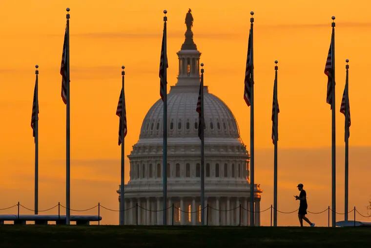 A pedestrian is silhouetted against a sunrise at the U.S. Capitol Building in Washington last Monday, a day before the midterm elections.