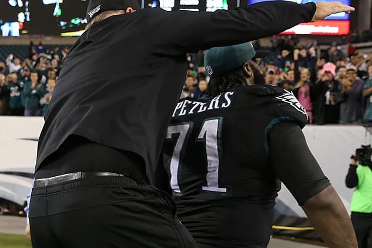 Eagles head coach Chip Kelly leaps on Jason Peters' back after the Eagles beat the Giants. (David Maialetti/Staff Photographer)
