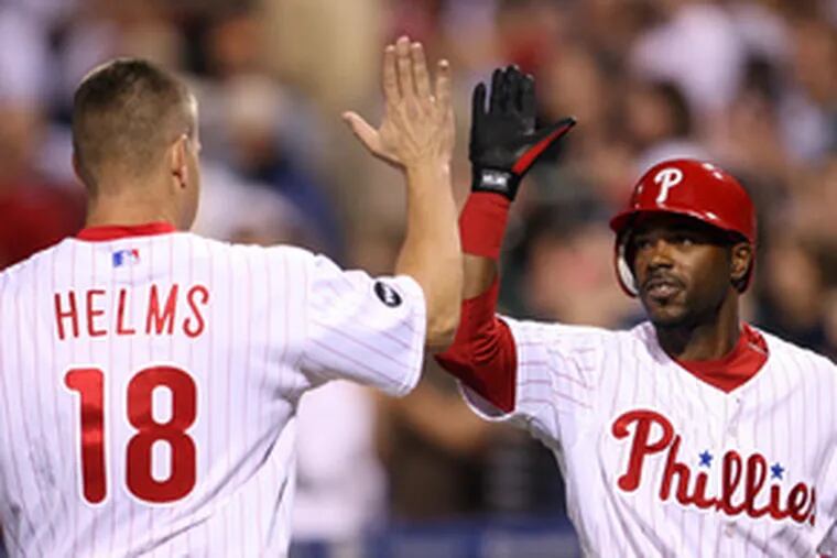 Wes Helms celebrates with Jimmy Rollins after Helms&#0039; eighth-inning hit that scored winning run.