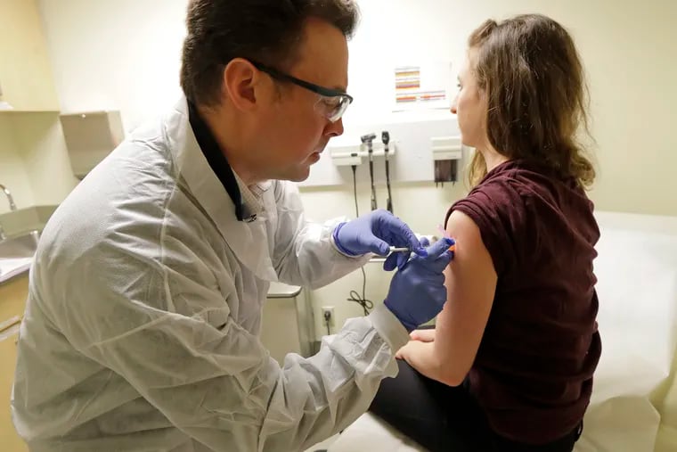 Pharmacist Michael Witte (left) gives Rebecca Sirull a shot in the first-stage safety study clinical trial of a potential vaccine for COVID-19, the disease caused by the new coronavirus, on March 16 at the Kaiser Permanente Washington Health Research Institute in Seattle.