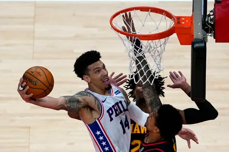 76ers forward Danny Green (14) goes in for a basket as the Atlanta Hawks' John Collins (20), right, and Bruno Fernando (24) defend during the first half.