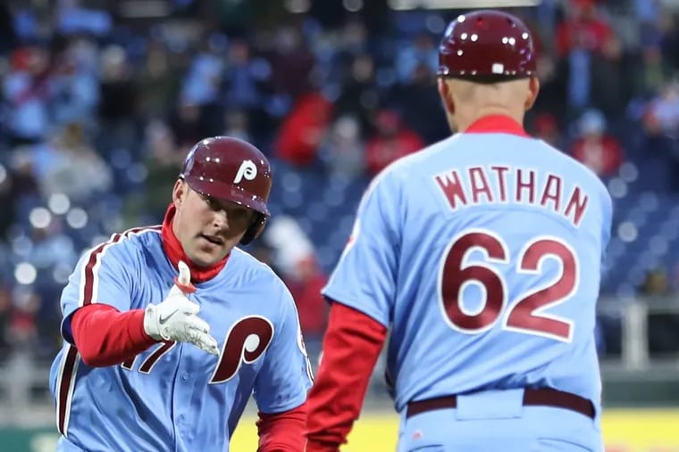 Rhys Hoskins, left,  is congratulated by Phillies third-base coach Dusty Wathan after his solo home run against the Pittsburgh Pirates last month. CHARLES FOX / Staff Photographer