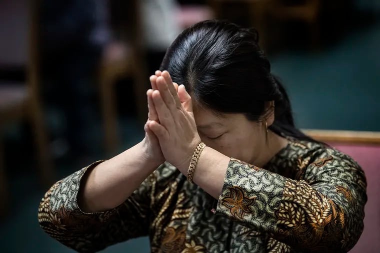 Churchgoer Nanik Oei prays during a service at the St. Thomas Aquinas Church in South Philly