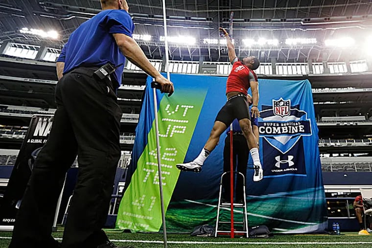 Combine staff member Mike Kozak watches as tight end John Reese tests in the vertical leap. (Tony Gutierrez/AP)