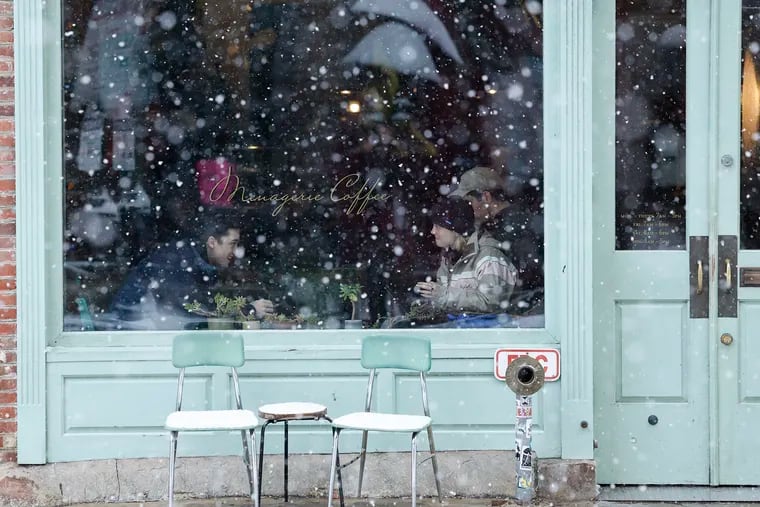 Customers sit inside Menagerie Coffee while snow falls in Old City on Friday.