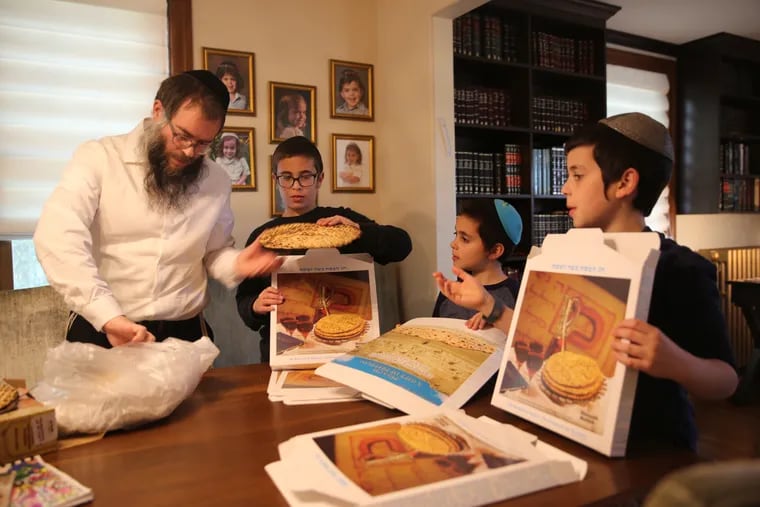 In preparation for Passover, Rabbi Yitzchok Kahan and three of his children (from left) Chaim, Levi, and Zev package matzo in their home in Medford to give to community members.