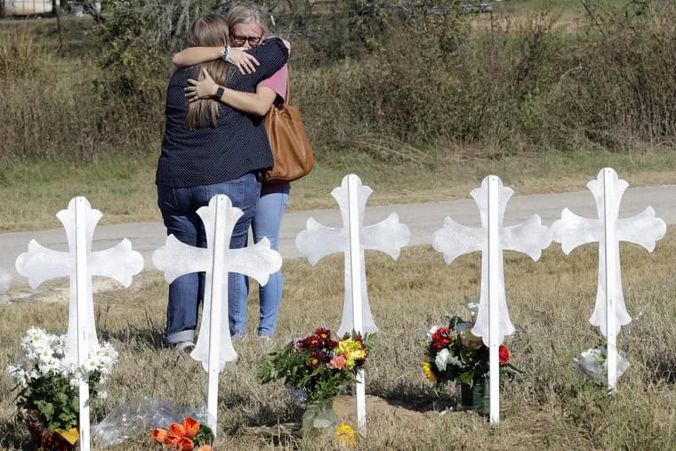 Two women hug at a makeshift memorial for the First Baptist Church shooting victims Tuesday, Nov. 7, 2017, in Sutherland Springs, Texas. A man opened fire inside the church in the small South Texas community on Sunday, killing more than two dozen and injuring others. (AP Photo/David J. Phillip)