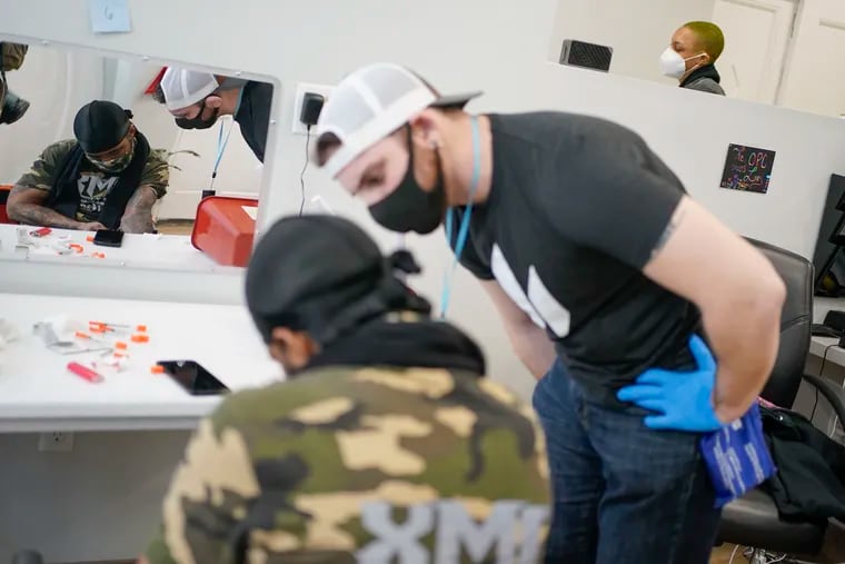 Brian Hackel, right, an overdose prevention specialist, helps Steven Baez, a client suffering addiction, find a vein to inject intravenous drugs at an overdose prevention center, at OnPoint NYC in New York, N.Y., in February.