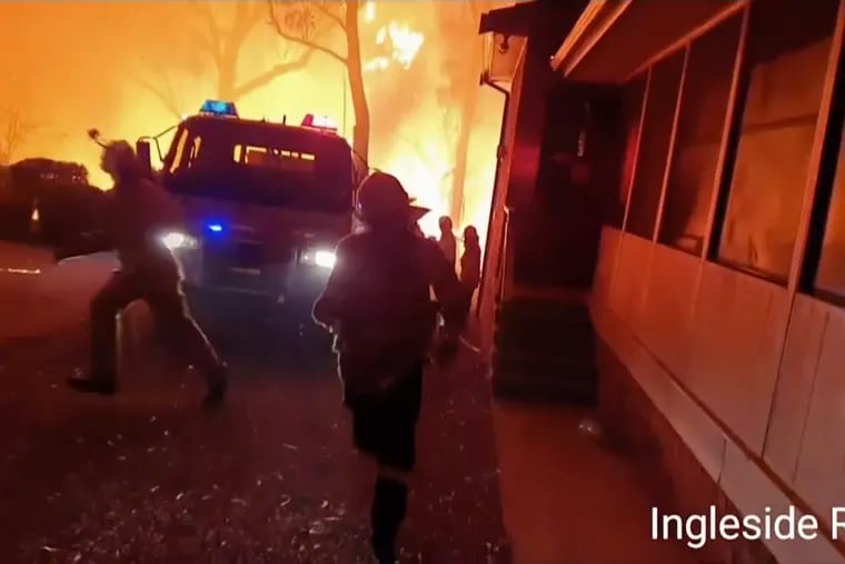 This image made from video taken on Dec. 22, 2019, and provided Dec. 25, 2019, by Ingleside Rural Fire Brigade, shows the wildfire behind an emergency vehicle near property on Hat Hill Road in Blackheath, New South Wales.  Australian authorities have warned that the fires in New South Wales could fester for months, causing more angst for exhausted firefighters.(Ingleside Rural Fire Brigade via AP)