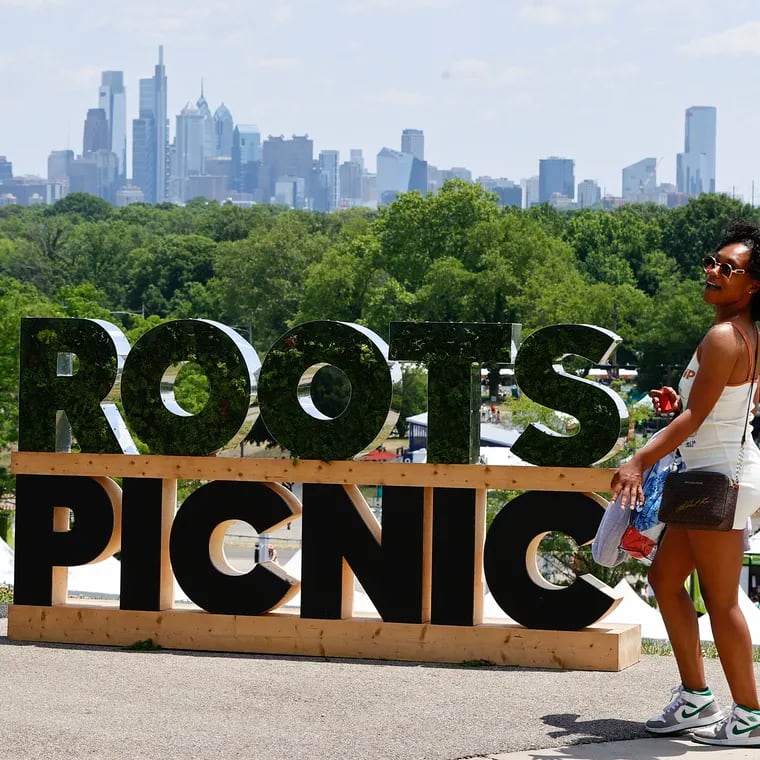 Bri Smith of West Philadelphia poses by the Roots Picnic sign with the city skyline in the background before the start of day 2 of the Roots Picnic at the Mann Center for the Performing Arts on Sunday, June 4, 2023.