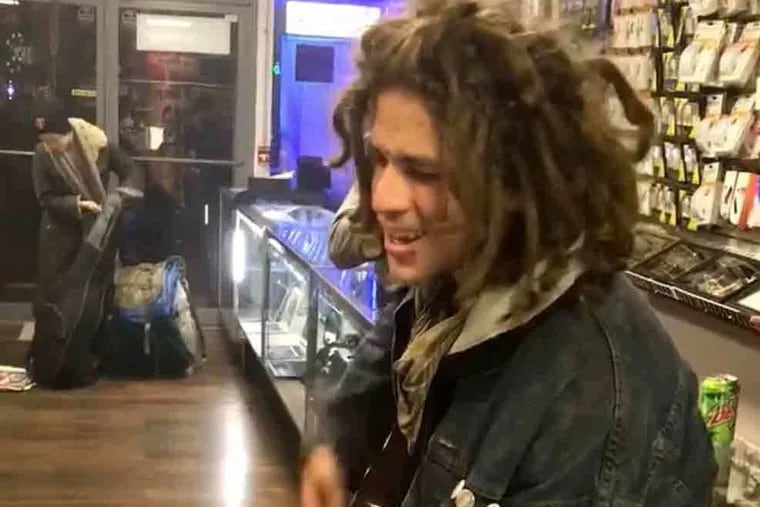 Photo of an unidentified man playing his guitar as he tries to sell it to Luis Payan at Payan's electronics store on Kensington Ave., November, 2018. (Courtesy Luis Payan, Video screen capture)