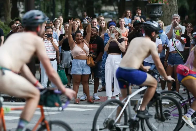 People at Rittenhouse Square react as the annual Philly Naked Bike Ride goes by in Philadelphia in 2022.