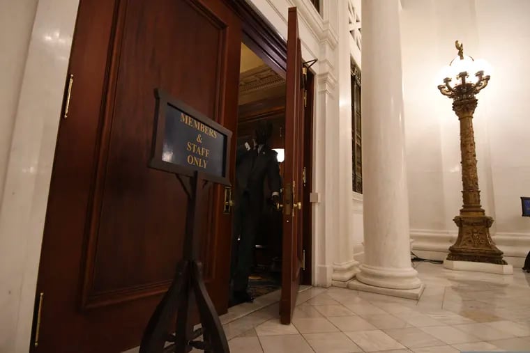 A state lawmaker prepares to exit through the doors at the back of the House chamber in Pennsylvania's Capitol, Wednesday, March 29, 2019, in Harrisburg, Pa. The doors lead to a room known as the "lobbyist room" before House officials closed it this year. (AP Photo/Marc Levy)