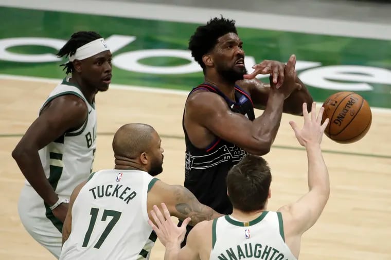 Joel Embiid is surrounded by Bucks and fouled by P.J. Tucker (17) on Thursday.