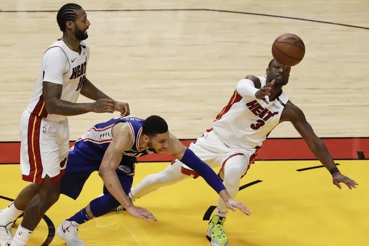 Heat guard Dwyane Wade falls down reaching for the basketball with teammate James Johnson against Sixers guard Ben Simmons during the third quarter in game four of the Eastern Conference quarterfinals on Saturday.