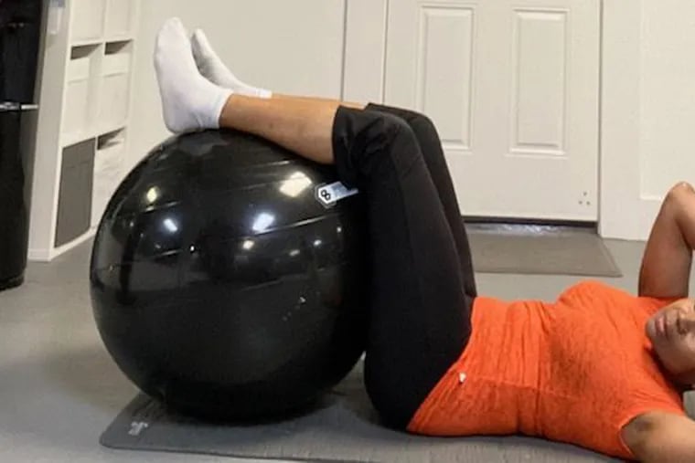 Demonstrating beginner floor crunches and a twist with a stability ball.