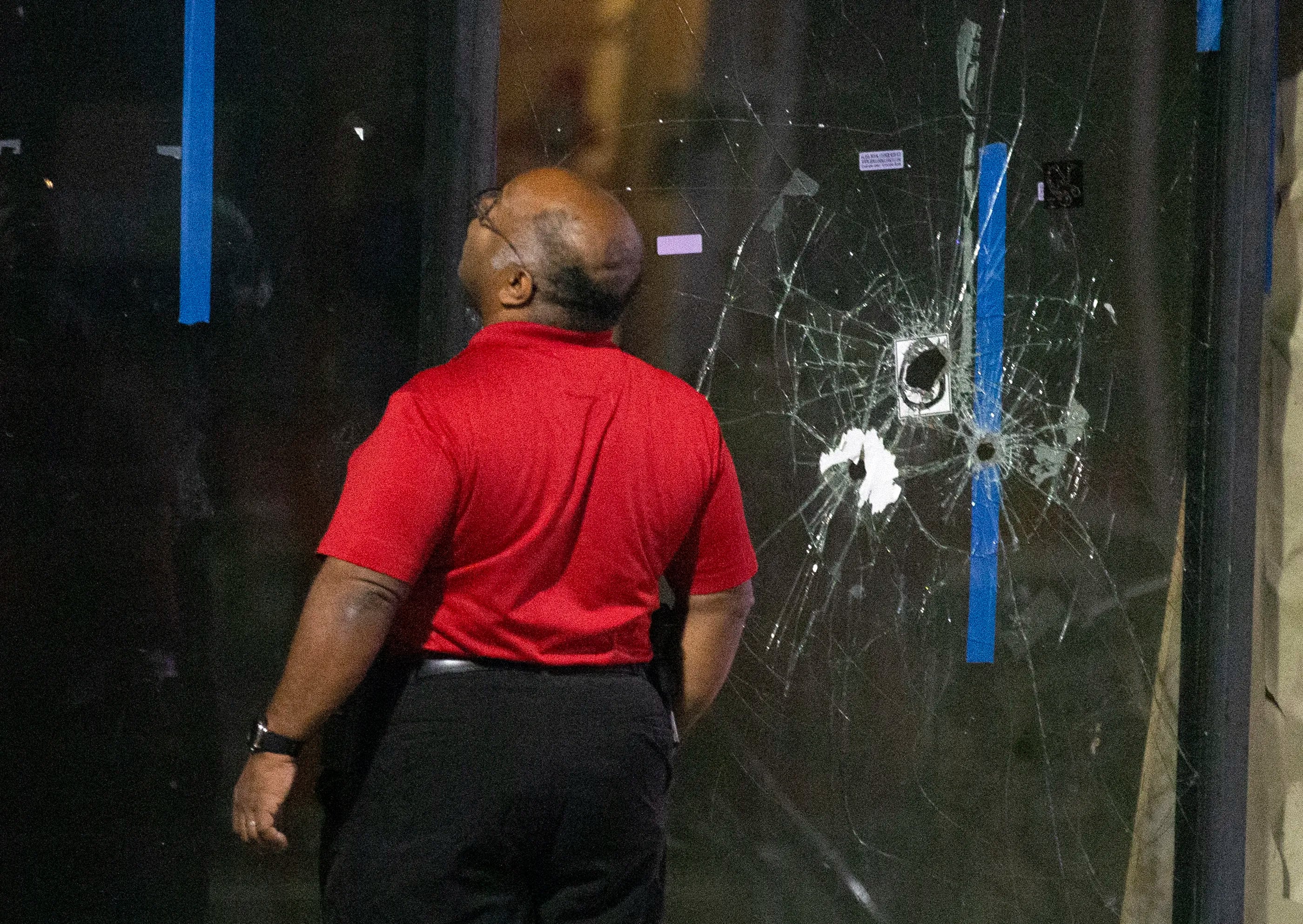 Philadelphia Police detectives look a bullet scarred window at the scene of a shooting on and near South Street that left 3 dead and 11 wounded.