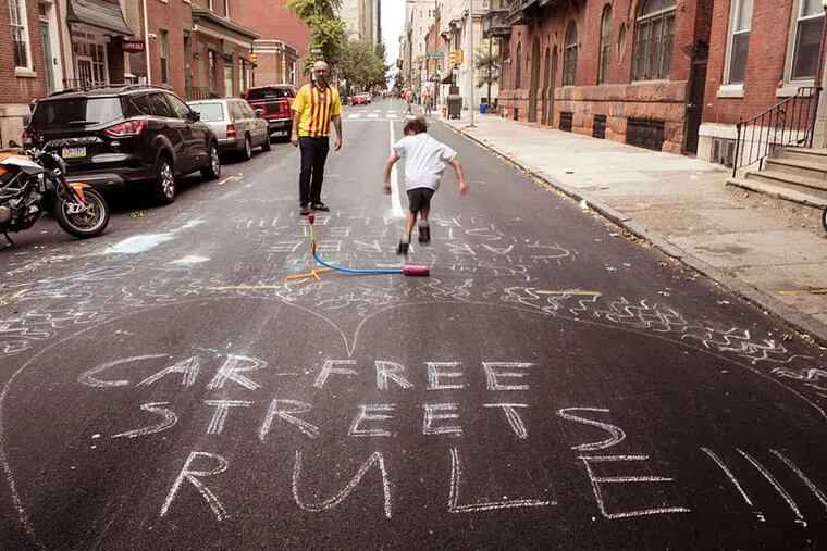 John Smith and his son Maxwell take advantage of Philadelphia's blocked city streets during the papal visit to make some chalk art and launch an air rocket. Sunday, September 27, 2015, Philadelphia, Pennsylvania. ( MATTHEW HALL / For The Inquirer )