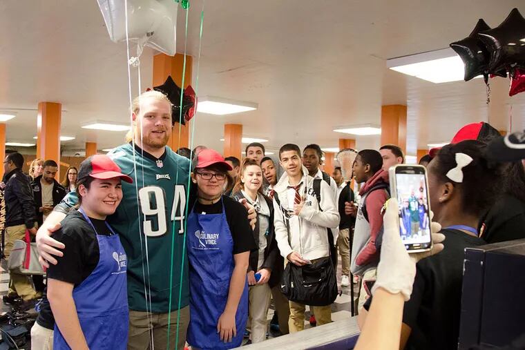 Eagles tackle Beau Allen  with Northeast High School students Anna Okropiridze (left) and Jennica Nugent. Both Okropiridze and Nugent are part of the school's new "Wellness Corner," which is responsible for serving healthy breakfasts to students . ( Rachel Wisniewski / Staff Photographer )