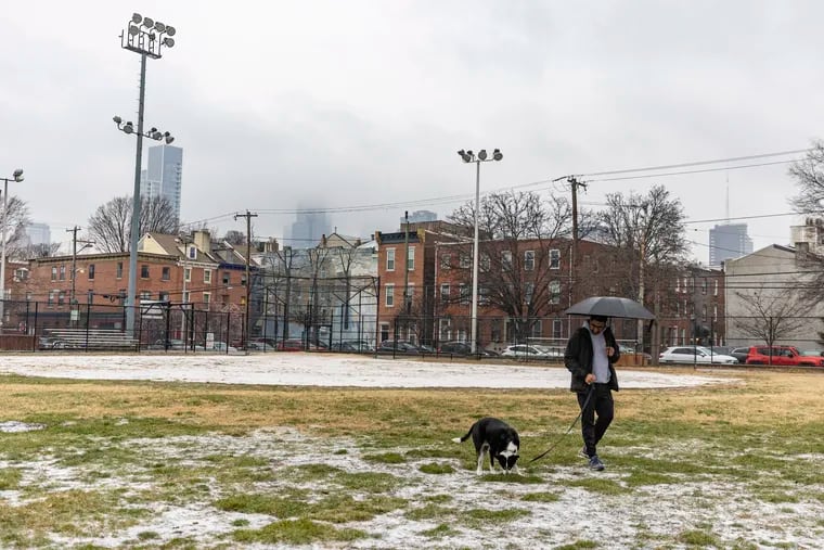 Anuj Basil, 40, of Bella Vista, walks his dog Mathey, 8, at the Palumbo Recreation Center  in Philadelphia, on Saturday, Jan. 6, 2024. “It’s nice to get a little snow, but I was hoping for more,” Basil said.