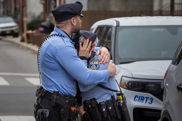 A Philadelphia police officer is consoled Monday after a visit to the memorial for Temple University Police Officer Christopher Fitzgerald, who was shot and killed in the line of duty Saturday night. The memorial is at Bouvier Street and Montgomery Avenue in Philadelphia.