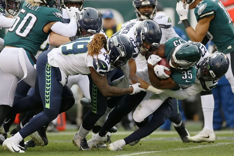 Seahawks linebacker Shaquem Griffin (49), running back Travis Homer (25), and free safety Marquise Blair (27) bring down Eagles running back Boston Scott.