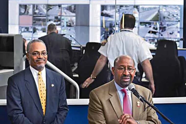 Chief of Staff and Deputy Mayor for Public Safety Everett Gillison (left) and Mayor Michael Nutter comment outside the glassed-in Real-Time Crime Center (rear) with all its video monitors inside the Delaware Valley Intelligence Center, following a tour of the new facility June 28, 2013. ( TOM GRALISH / Staff Photographer )