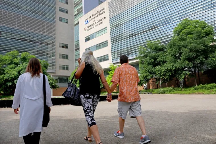 Dean DeMoe, right, and his wife, Deb DeMoe, center, of North Dakota, walk across the campus of Washington University School of Medicine on May 30, 2018, with Tamara Donahue, to begin examinations for a study of people living with dominantly inherited Alzheimer's disease. Dean DeMoe has testing at the medical school yearly as part of the study. Donahue is the study coordinator. (Christian Gooden/St. Louis Post-Dispatch/TNS)