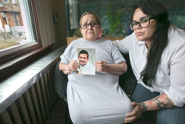 Wanda Davila, with her daughter Carmen Pagan, right, holds a photo of her son Richard Davila who was killed by a stray bullet in Fairhill.