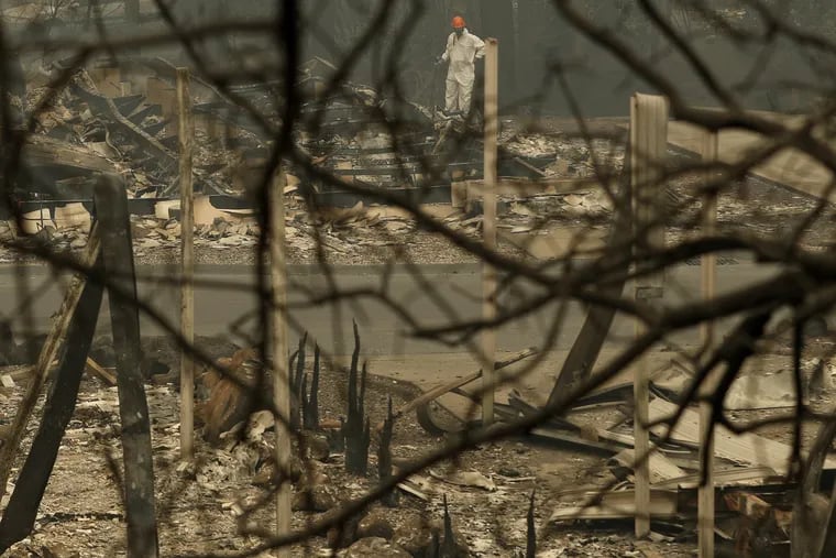 A search and rescue worker searches for human remains at a burned out trailer park from the Camp Fire, Tuesday, Nov. 13, 2018, in Paradise, Calif. The deadliest, most destructive blaze in California history has killed multiple people. (AP Photo/John Locher)