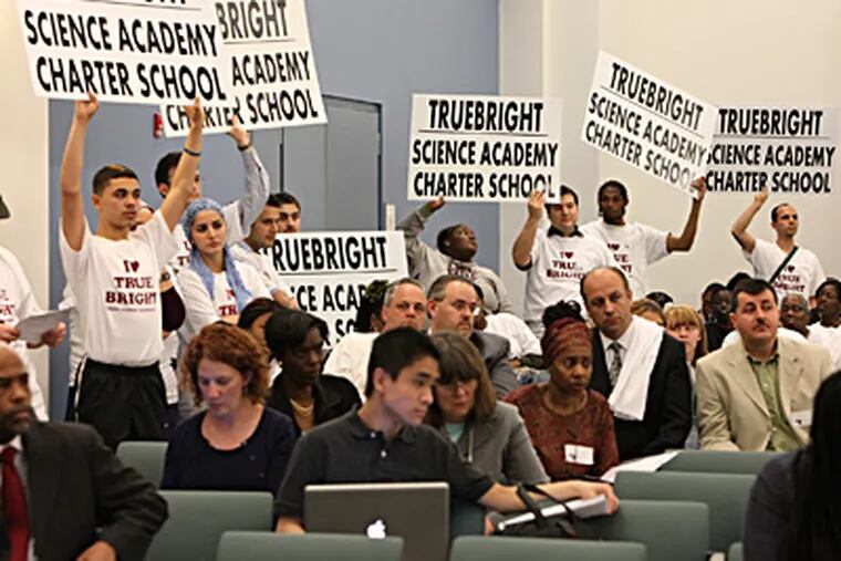 Truebright Science Academy supporters hold their posters high at the SRC hearing. It is one of more than 130 charters nationwide run by followers of a Turkish imam that are drawing scrutiny. (Steven M. Falk / Staff Photographer)