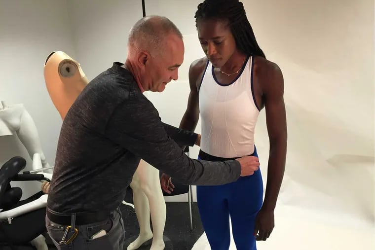 Mark Sunderland, a Philadelphia University textile engineer and professor, adjusts a prototype seamless suit for Chierika Ukogu, who is rowing for the Nigerian team at the Olympics. “I don’t feel constricted in any way,” she said. TOM AVRIL / Staff