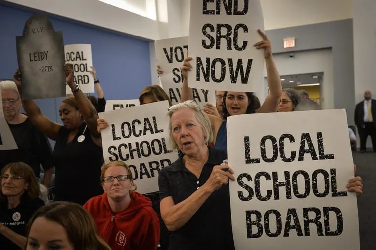 Parents, teachers, and education activists shout and hold signs calling for the end of the SRC during the final School Reform Commission meeting in June.