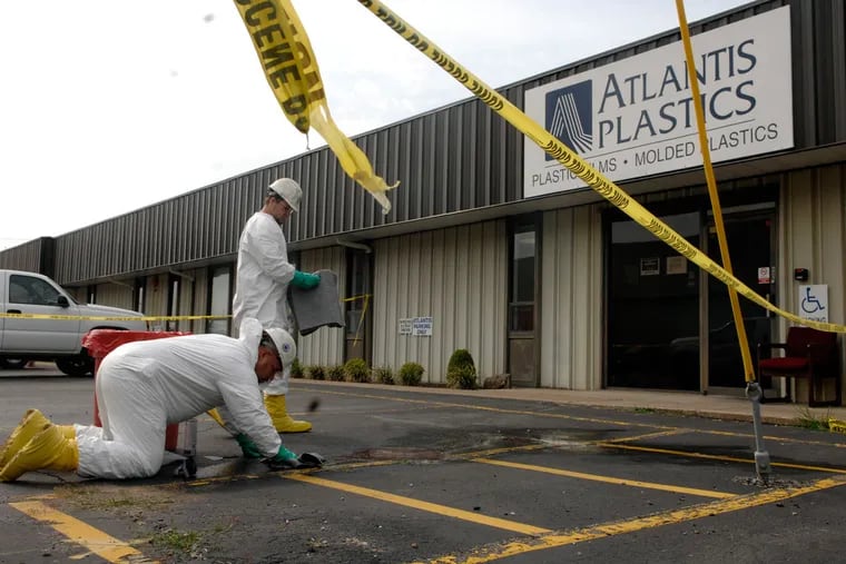 Workers with American Enviro-Services clean up an area surrounded by crime scene tape in front of the Atlantis Plastics plant in Henderson, Ky., where an employee shot and killed five people at the plant in Henderson before killing himself in June 2008.