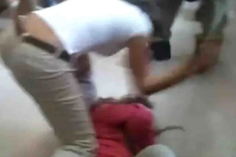 An Edison High School student assaults another student lying on a hall floor in a frame captured from a cellphone video.