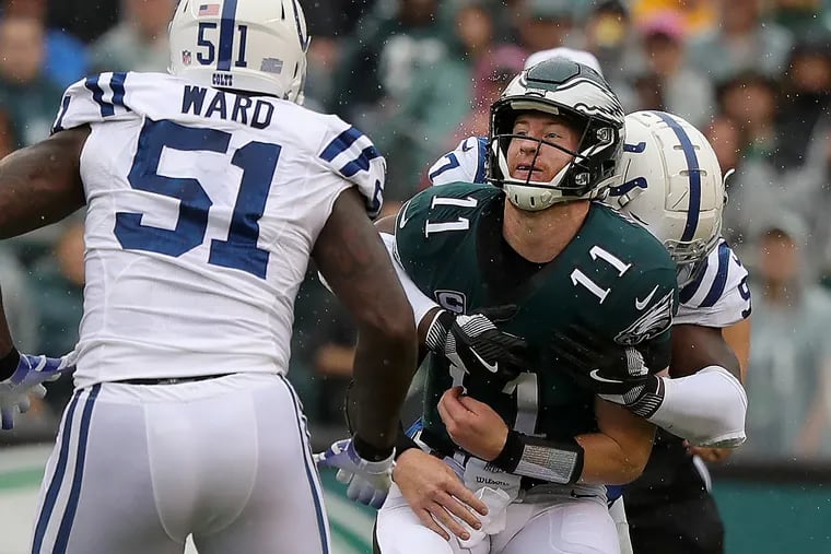 Carson Wentz is hit after throwing the ball by the Colts' Al-Quadin Muhammad (right).