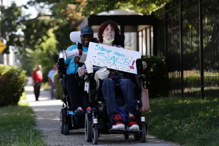 Inglis House resident Linda Litton rides along Belmont  Avenue to protest the sale of the Inglis House to a for-profit group on Friday.