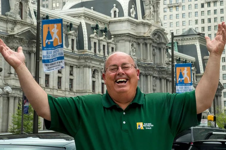 Jim Marino, 58, director of the city's Broad Street Run, outside City Hall underneath banners for the race. Three years ago, doctors discovered pancreatic tumors. He is now cancer-free.