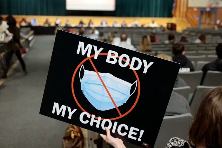 A woman holds a MY BODY MY CHOICE sign during the School District of Haverford Township school board meeting Thursday. The board voted yes to transition to optional masking.