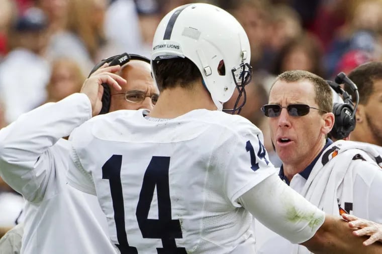 Penn State athletic trainer Tim Bream (right)  checks on injured quarterback Christian Hackenberg.
