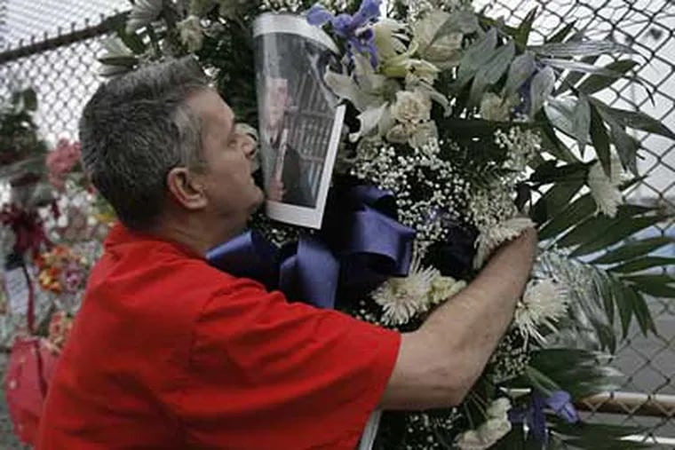 Billy Panas, father of slain son, Bill Panas Jr., hugs a wreath containing Bill Jr.' s photo at a shrine.  Bill Jr. was shot by an off-duty police officer in the city's Port Richmond section. (Akira Suwa / Staff Photographer )