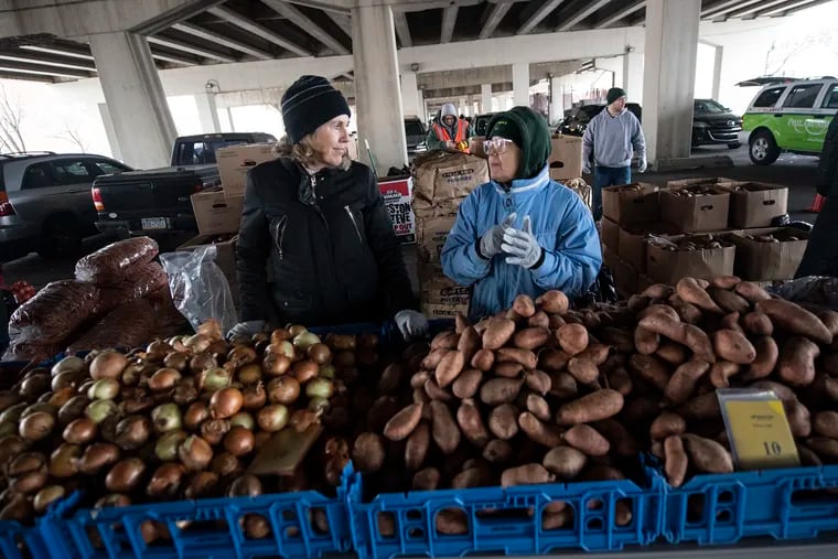 Volunteers, Lynn Balawejder, left, and Jacqueline Andrews, right, prepared to distribute free onions and potatoes to federal workers beneath I-95 at Tasker and Front Ave. on Jan. 23 as part of the first Emergency Market.