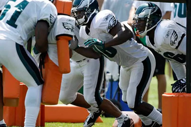 Omar Gaither, center, prepares to hit a blocker as the Eagles practice at the NovaCare Complex on Sunday. (David Maialetti / Staff Photographer)