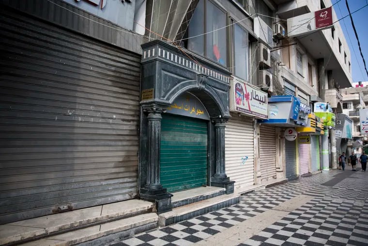 Palestinians walk next to closed shops in Gaza City, Tuesday, June 25, 2019, during a general strike against this week's economic conference in Bahrain that will kick off the Trump administration's plan for Mideast peace.