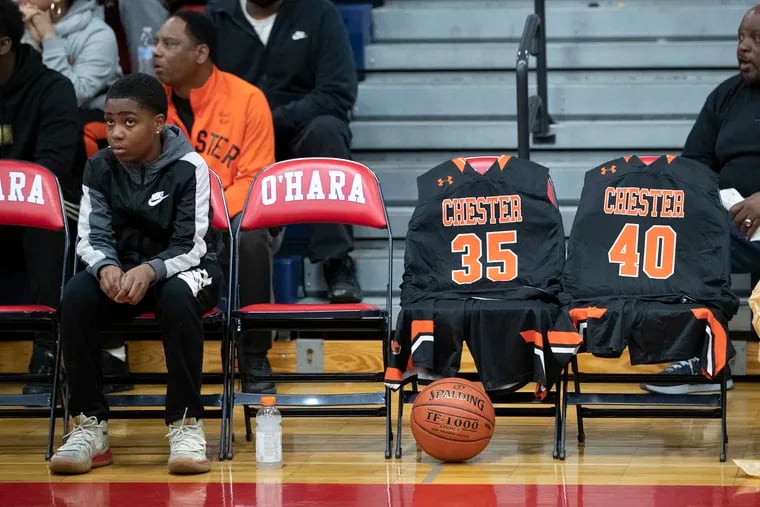 The uniforms of the late Edward Harmon, Jr. #35, and Jermere Clark, who remains hospitalized, of Chester are shown on chairs on the Chester bench before the second round game against Gratz in the PIAA Class 6A boys' basketball state tournament on March 11, 2020. Harmon, a Chester player was killed and Clark wounded the day before the game.  There was a ceremony and moment of silence before the game.