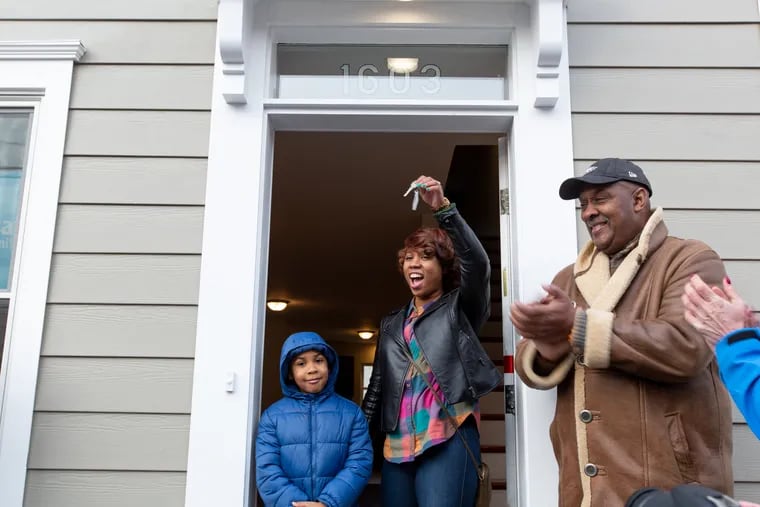 Niela Collins displays her keys while standing next to her six-year-old son, Nylan Blackman, and congressman Dwight Evans, after opening the door to her new home in North Philadelphia on Jan. 12. This is the final building of a 21-unit Habitat for Humanity development in North Philadelphia.